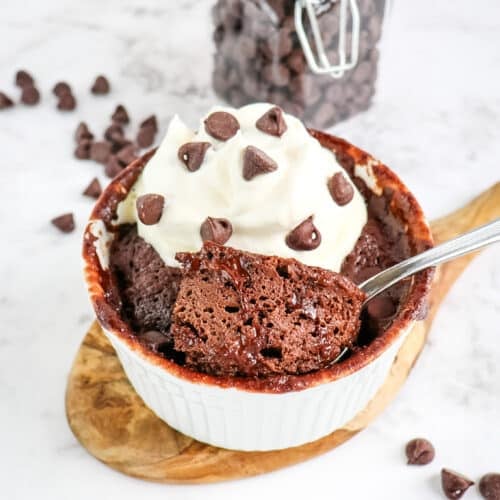Protein mug cake topped with whipped cream and chocolate chips.