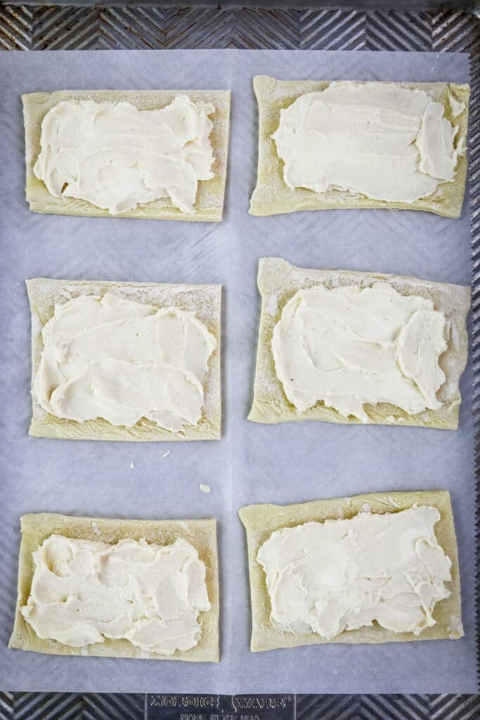 Cream cheese mixture spread over squares of puff pastry for making cream cheese blueberry Danish.