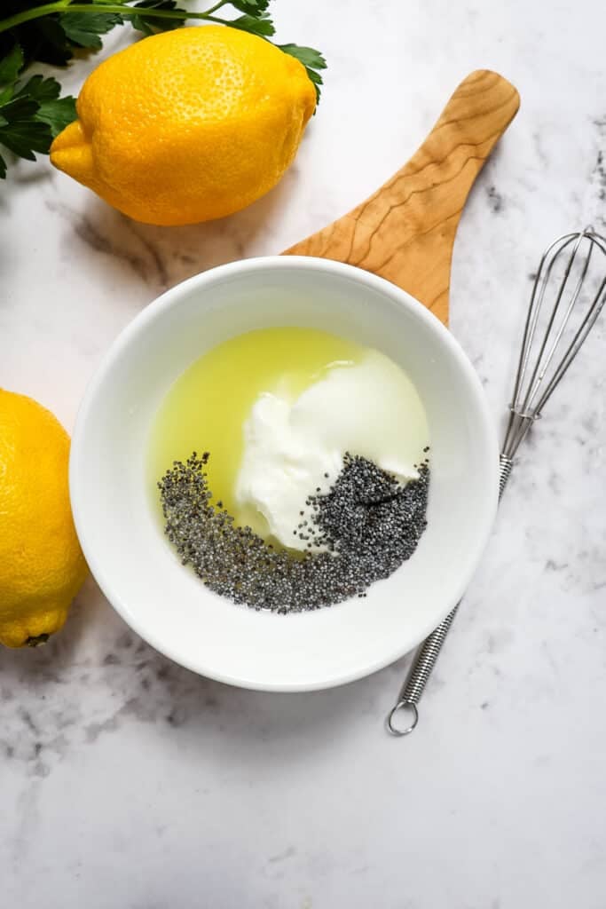 A small bowl with creamy lemon poppyseed dressing ready to be mixed with a small whisk.