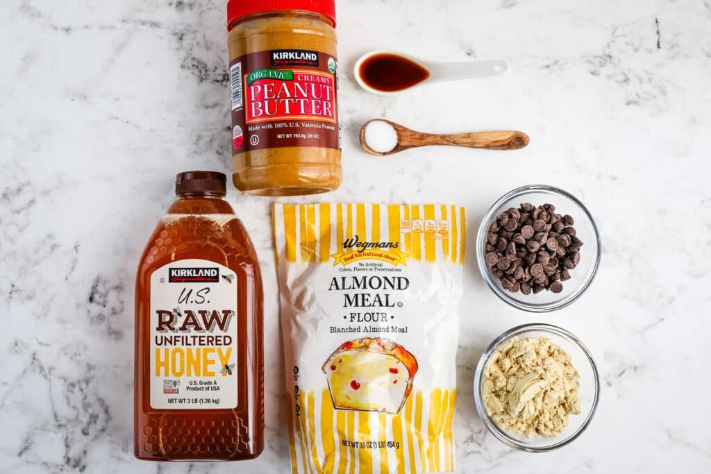 Ingredients needed to make low carb protein balls, including honey, almond flour, peanut butter, vanilla, salt, protein powder and chocolate chips.