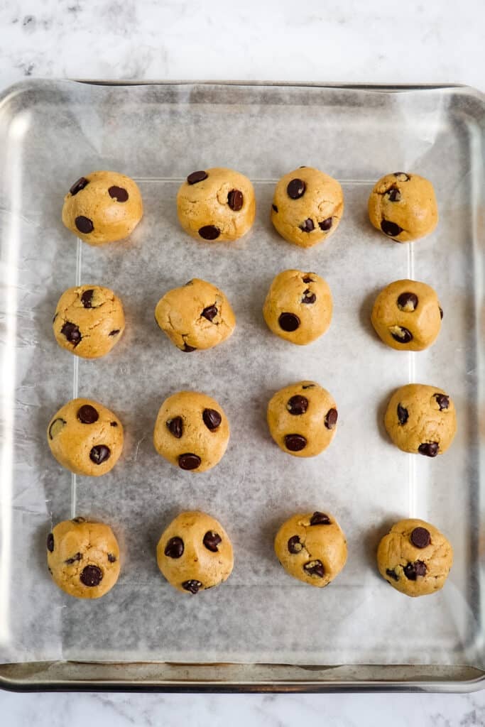 Cookie dough protein balls on a sheet pan lined with parchment paper.