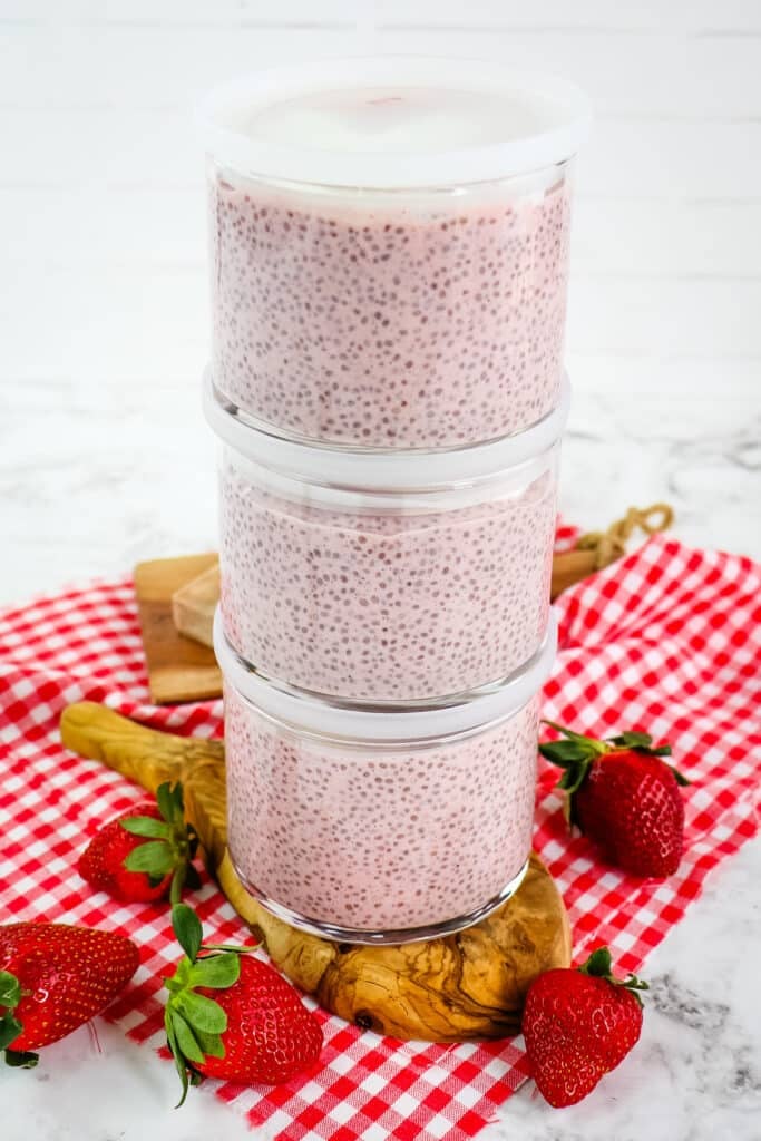 Strawberry chia pudding in clear glass meal prep containers, three containers stacked on top of each other.