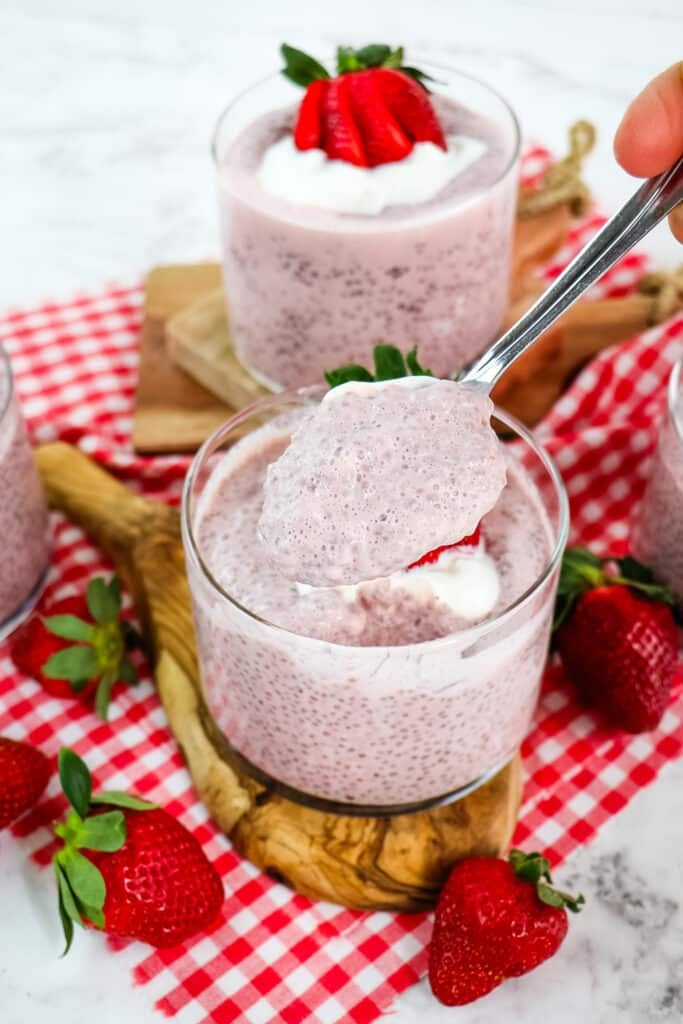 Strawberry chia seed protein pudding with spoon taking a bite out of the container.