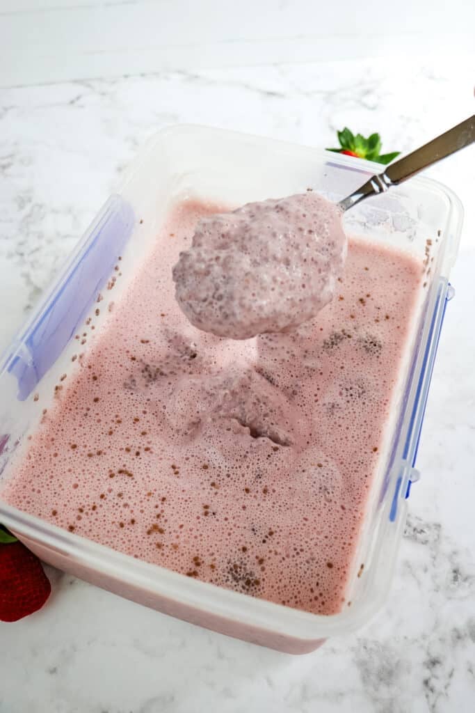 Strawberry chia seed protein pudding in a large container after being refrigerated.