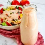 Creamy salsa dressing recipe in a tall jar with southwest salad and dressing in the background.
