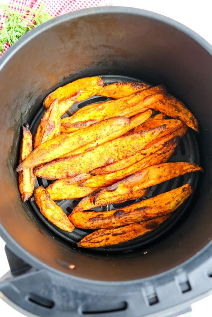 Sweet potato wedges in an air fryer basket that have just been cooked.