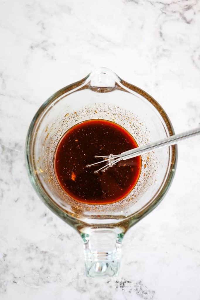 Mongolian beef sauce mixed together in a measuring cup with a small whisk.