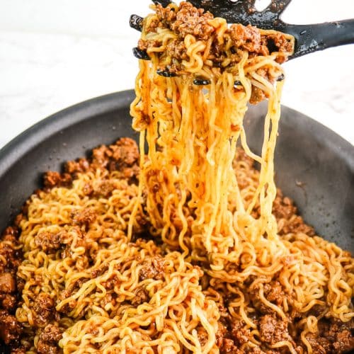 Beef and ramen noodles being mixed together in a skillet