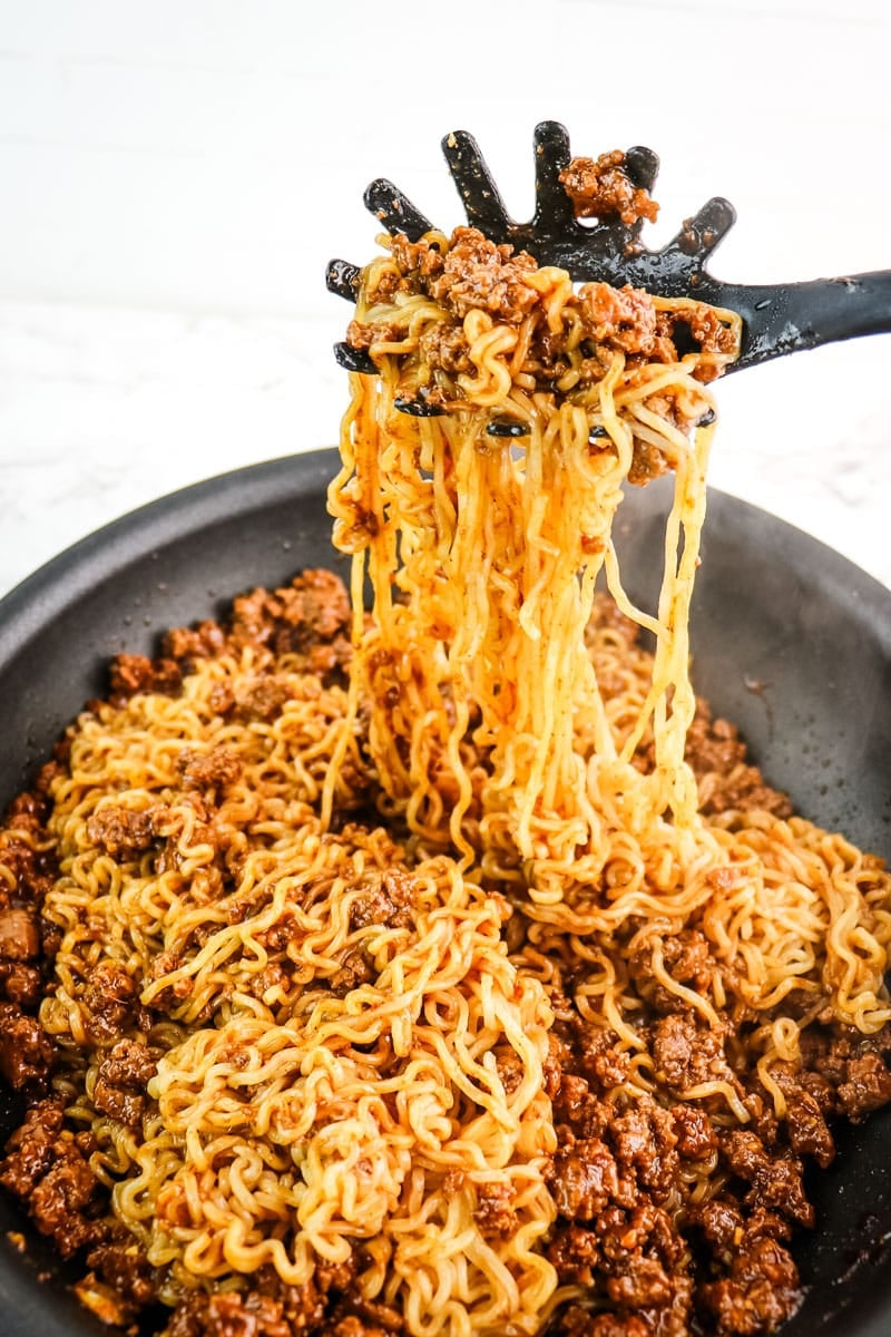 Beef and ramen noodles being mixed together in a skillet
