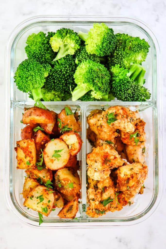 Garlic parmesan chicken and potatoes in a meal prep container with broccoli.