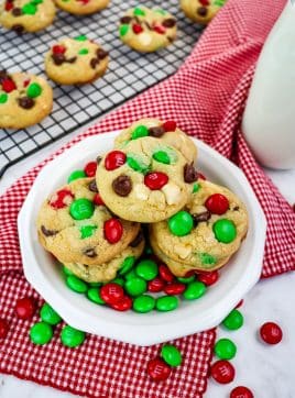 Plate of Christmas M&M cookies on a plate with red and green M&M's on the side.