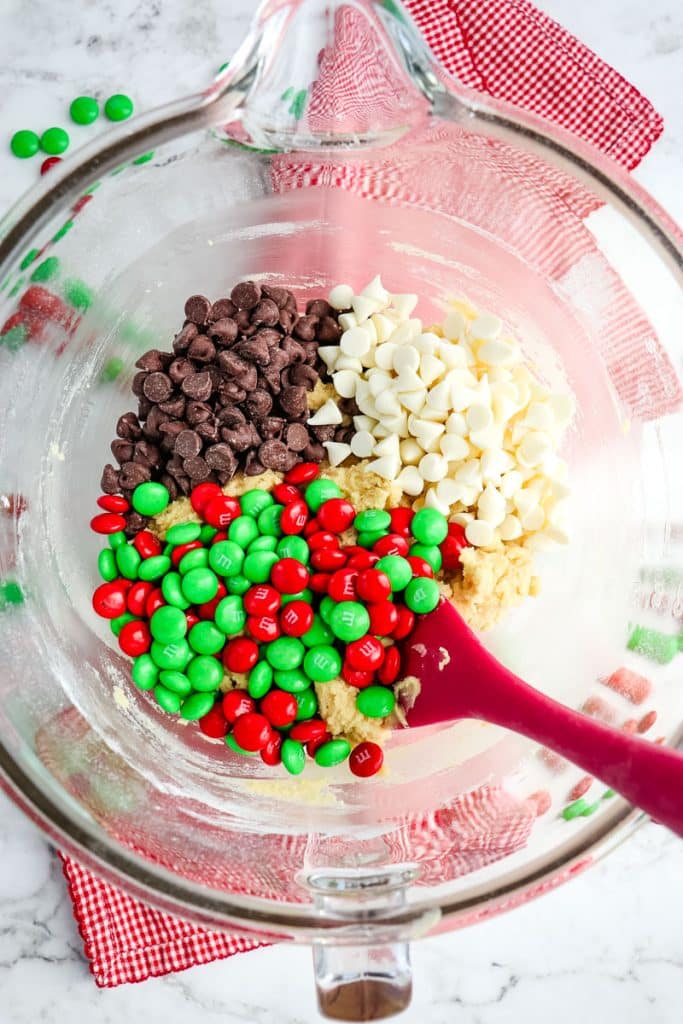 Bowl of cookie dough with white and semi-sweet chocolate chips and Christmas M&M's.