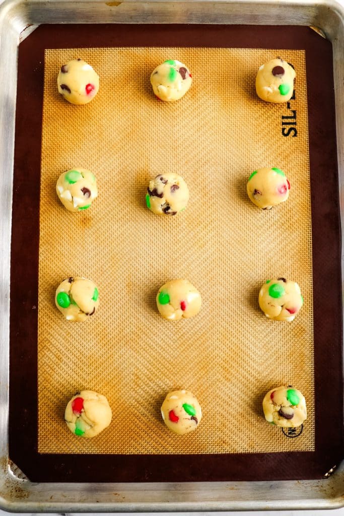 Cookie dough balls on a lined baking sheet before being baked.