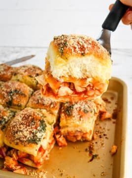 A single bbq slider being lifted off sheet pan with a spatula.