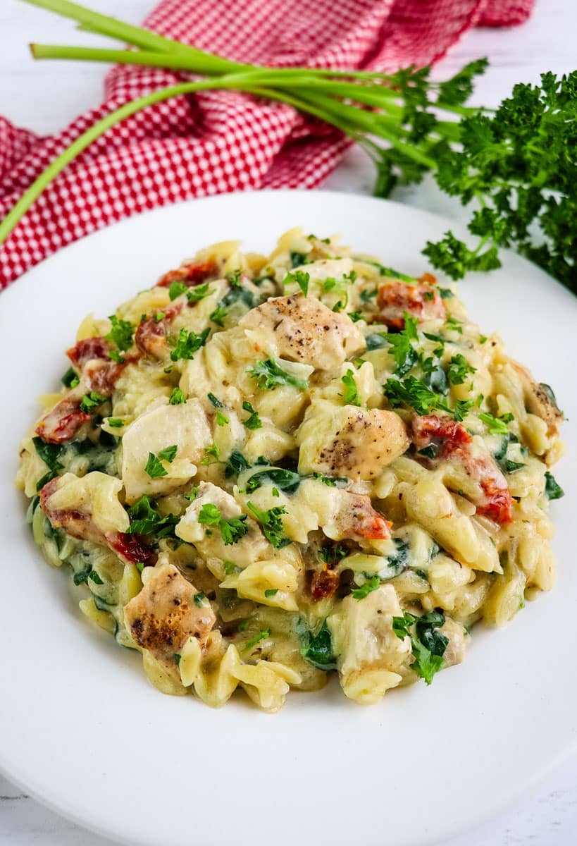 Marry me chicken orzo on a plate topped with chopped parsley.