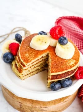 Cottage cheese protein pancakes stacked on a plate with single bite taken out.