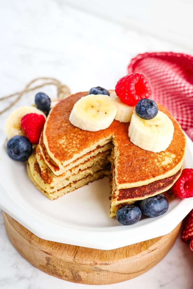 Cottage cheese protein pancakes stacked on a plate with single bite taken out.