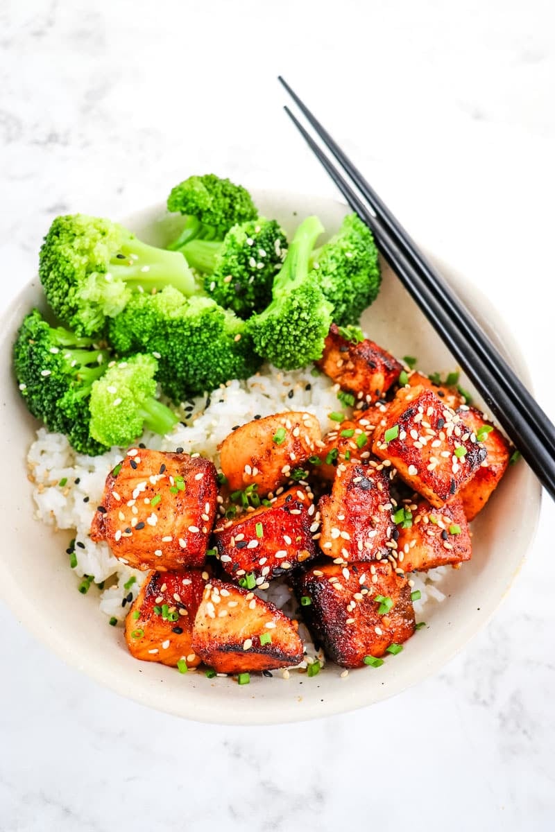 Crispy salmon bites in a bowl over rice with steamed broccoli on the side.