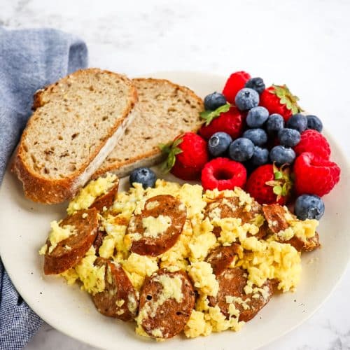 Egg sausage scramble on a plate with fresh berries and toast.