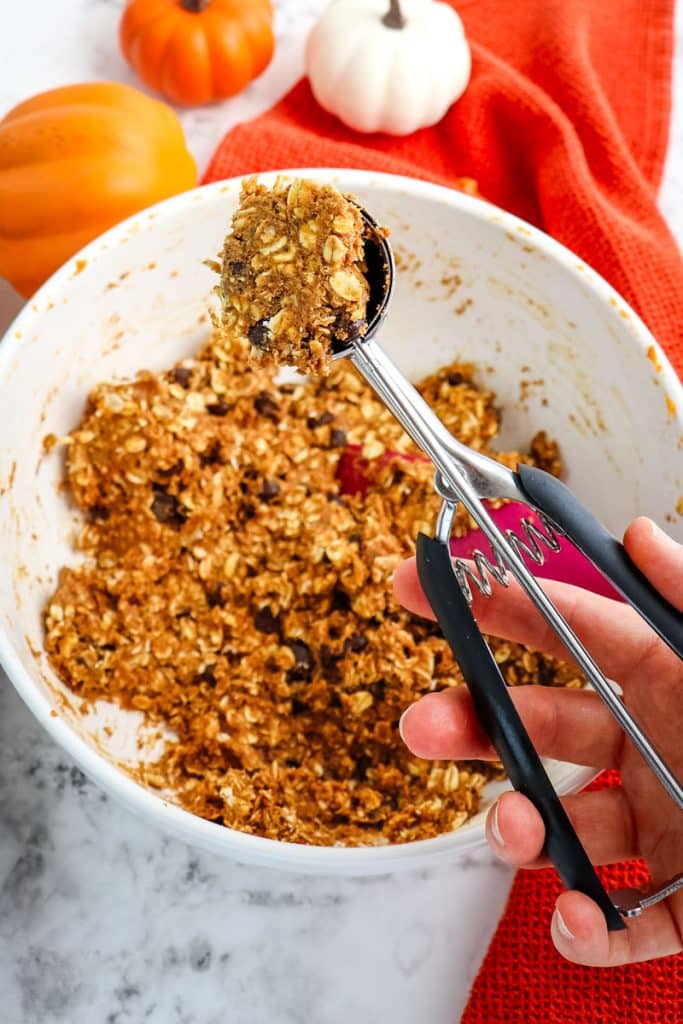 Pumpkin protein ball mixture being scooped from the bowl with a cookie scoop.