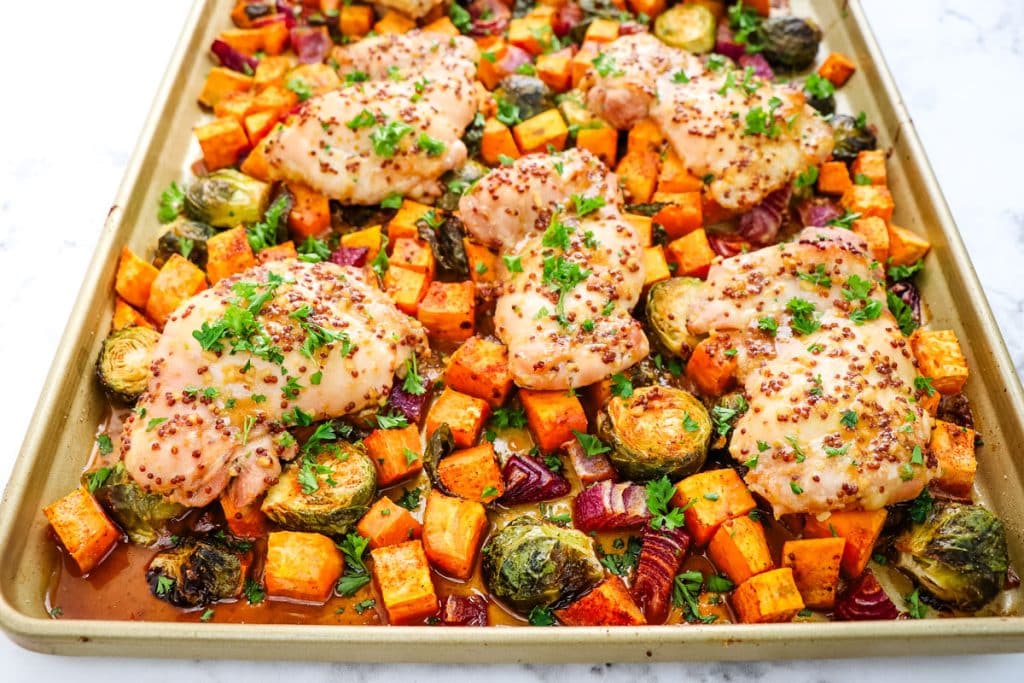 Sheet pan chicken thighs with maple dijon glaze and sweet potatoes, brussels sprouts on the side.