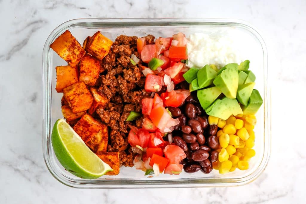 Taco bowl in a meal prep container with sweet potato, beef, salsa, beans, corn and cottage cheese.