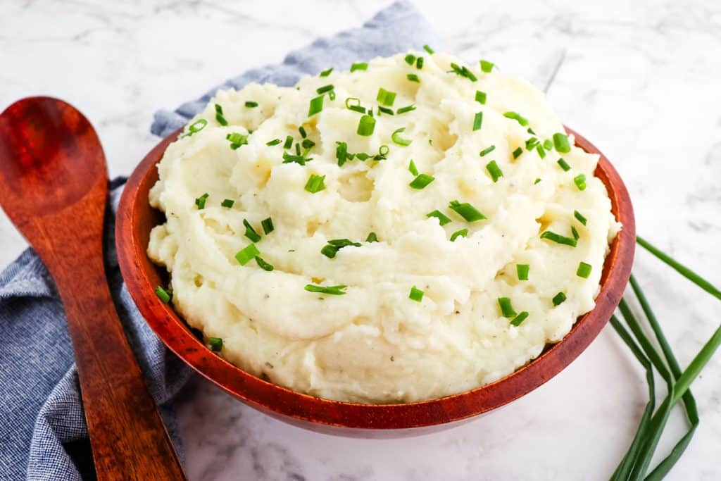 Boursin mashed potatoes in bowl topped with fresh chives.