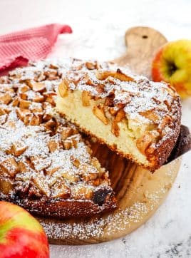 Slice of Dutch apple cake being lifted from entire cake.
