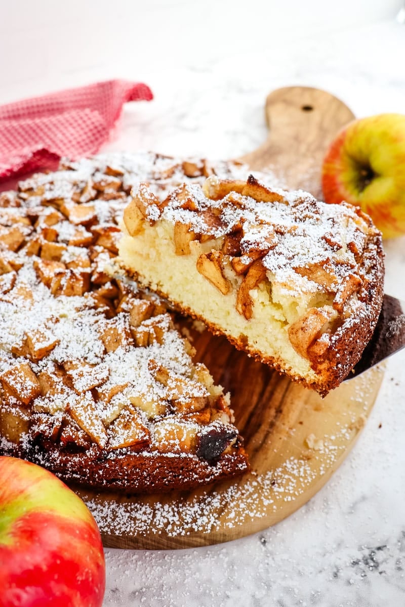 Slice of Dutch apple cake being lifted from entire cake.