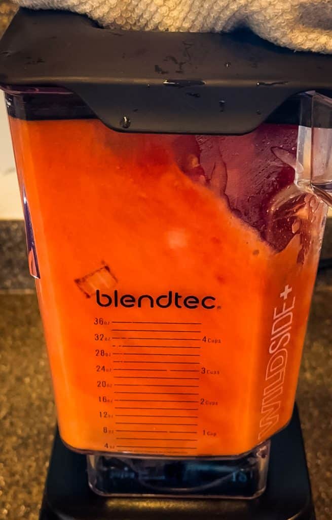 Tomatoes, onion and garlic being pureed together in a blender.