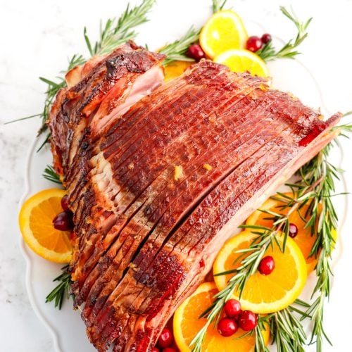 Orange glazed spiral ham from Costco, garnished with orange slices, fresh rosemary sprigs and cranberries.