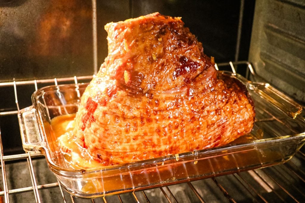 Orange glazed ham in the oven in a baking dish.