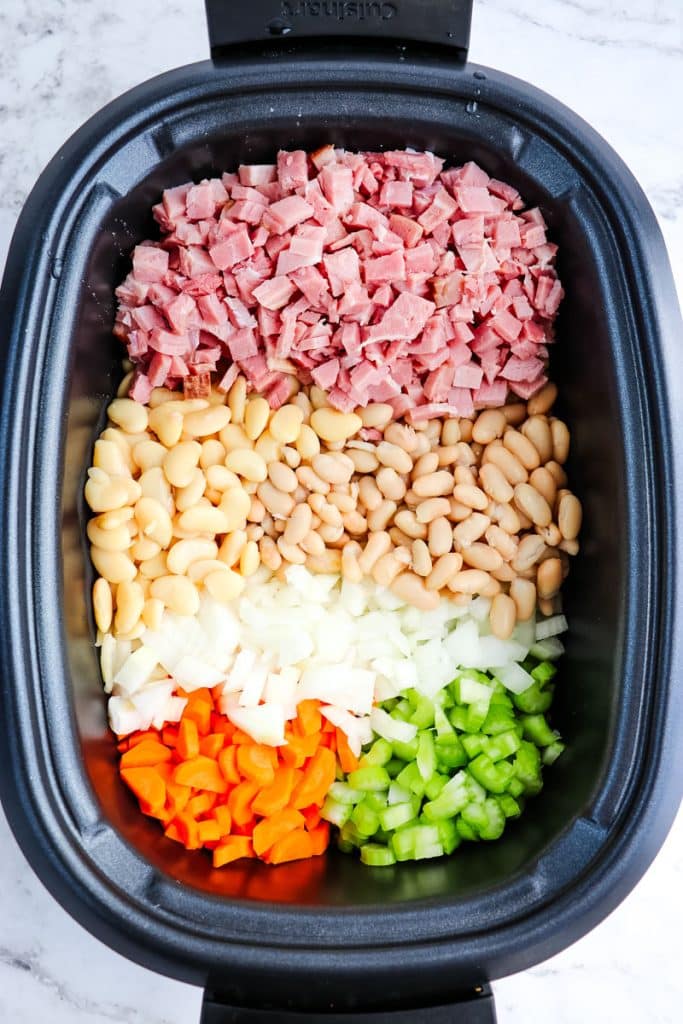 Ham and bean soup ingredients in a slow cooker before being cooked.
