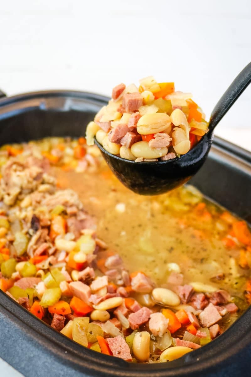 Ham and bean soup being ladled out of the slow cooker.