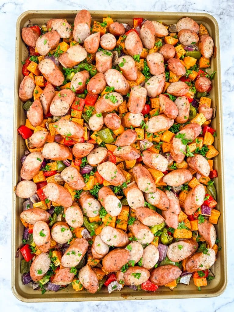 Oven baked sausage and peppers with sweet potatoes on a sheet pan.