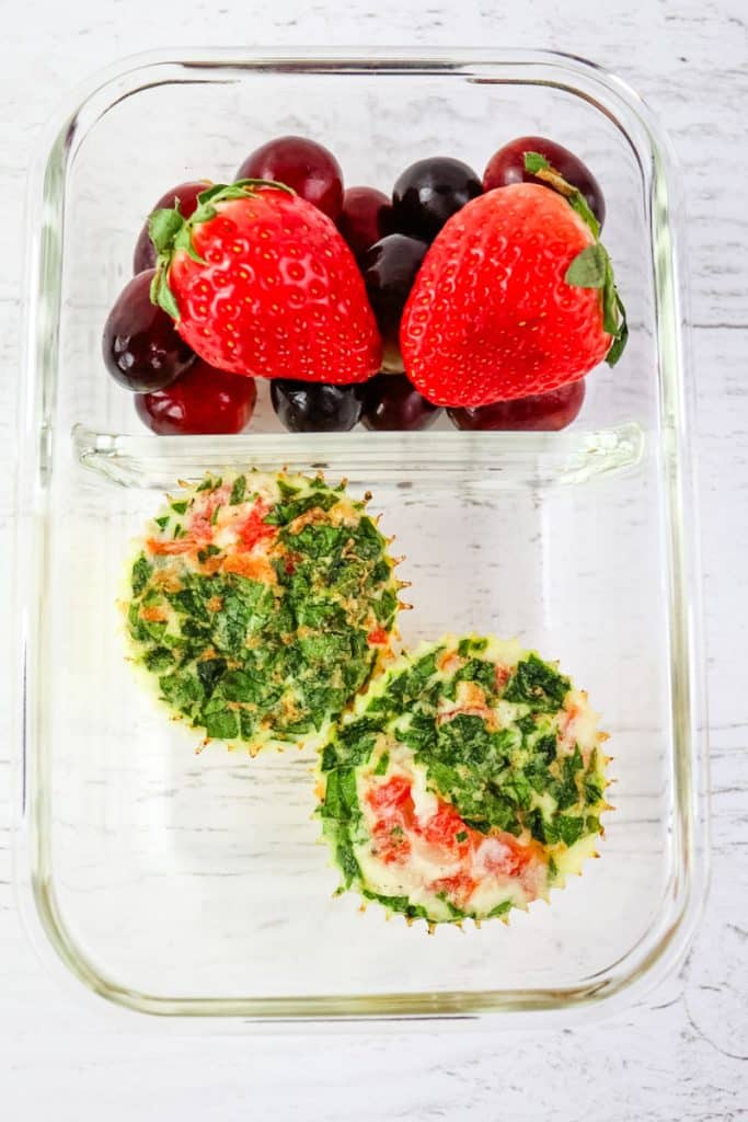 Two egg white bites in a glass meal prep container with fresh fruit.
