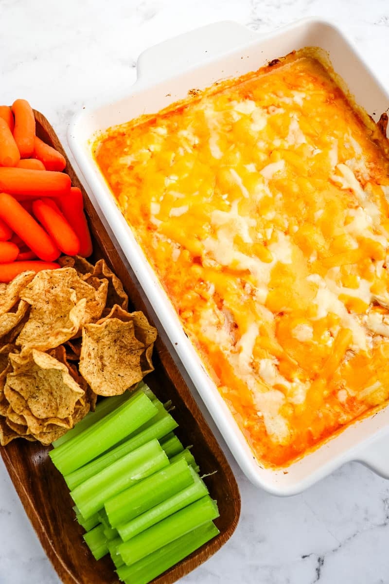 Healthy buffalo chicken dip served with celery sticks, scoop chips and baby carrots.