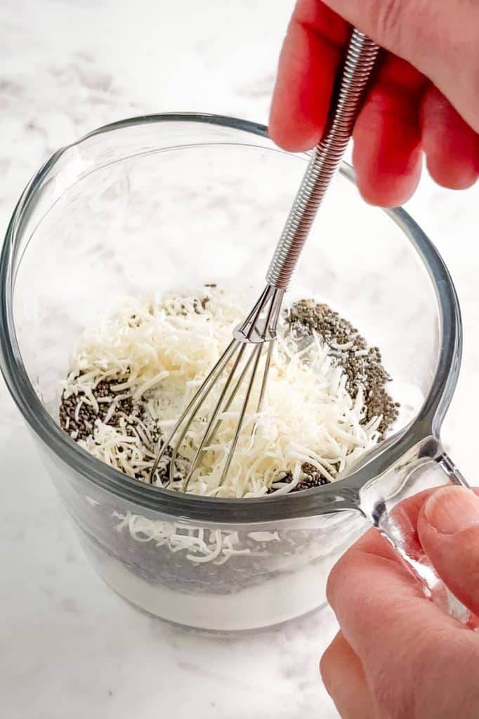 Ingredients for coconut milk chia pudding being whisked together in bowl.