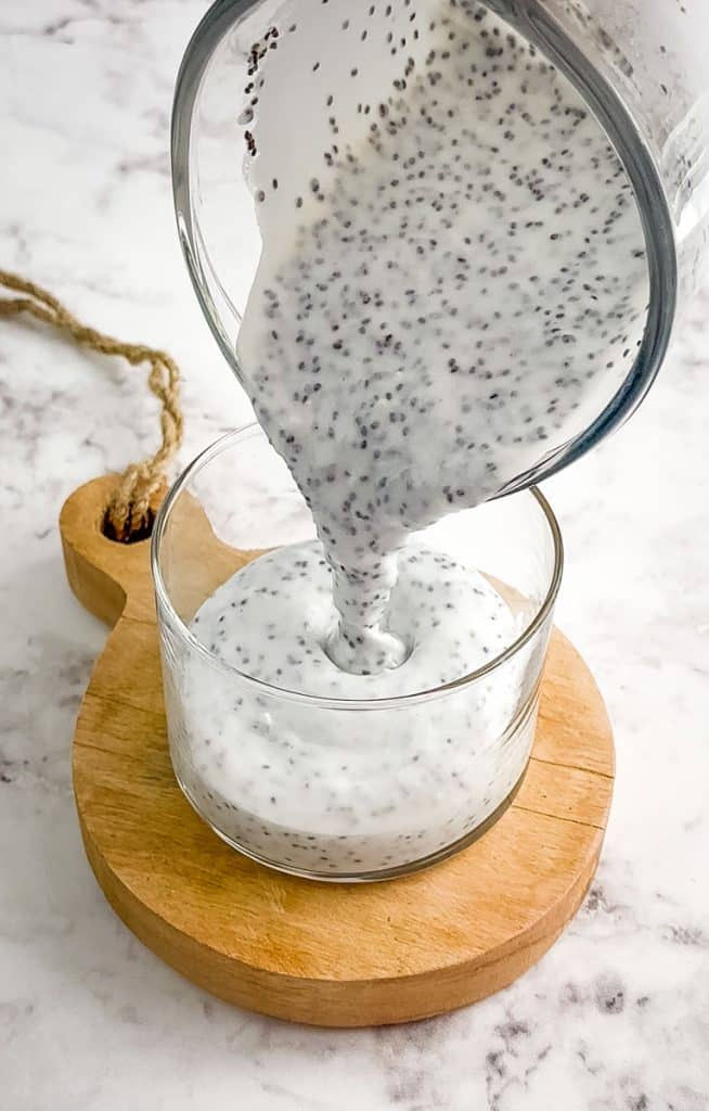 Coconut milk chia pudding with yogurt being poured into jar.