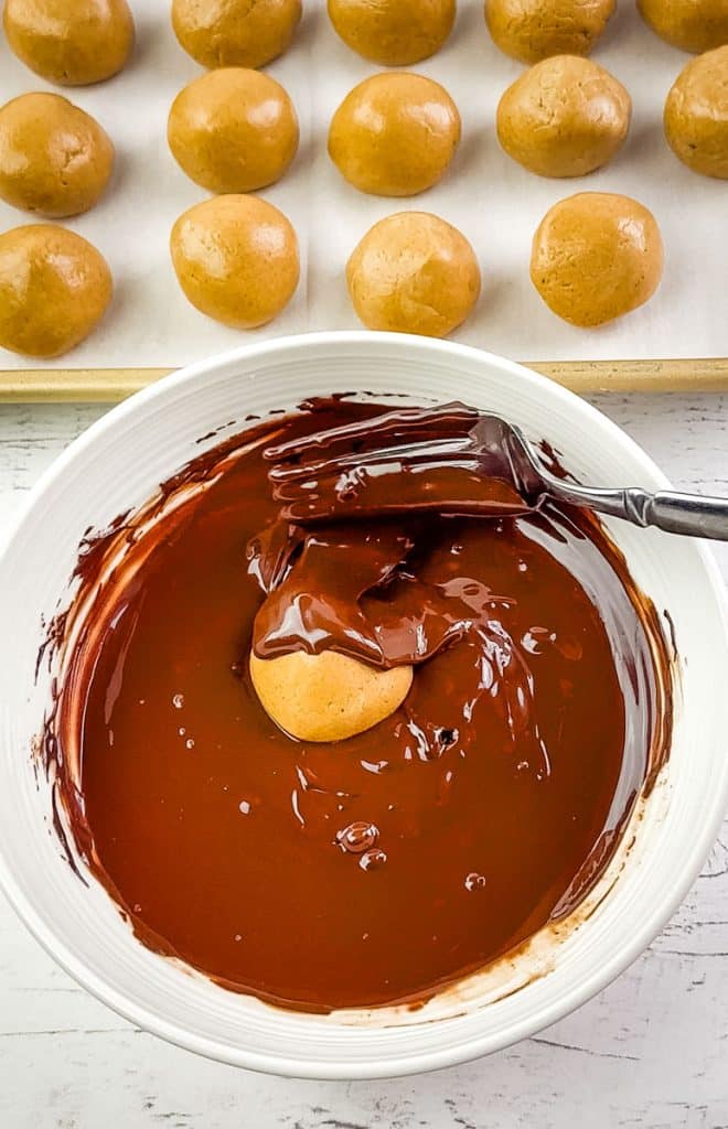 Peanut butter protein ball being coated in chocolate.