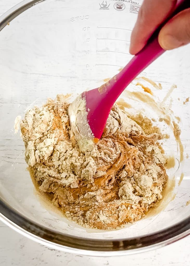 Ingredients being stirred together in a glass bowl for protein balls with protein powder.