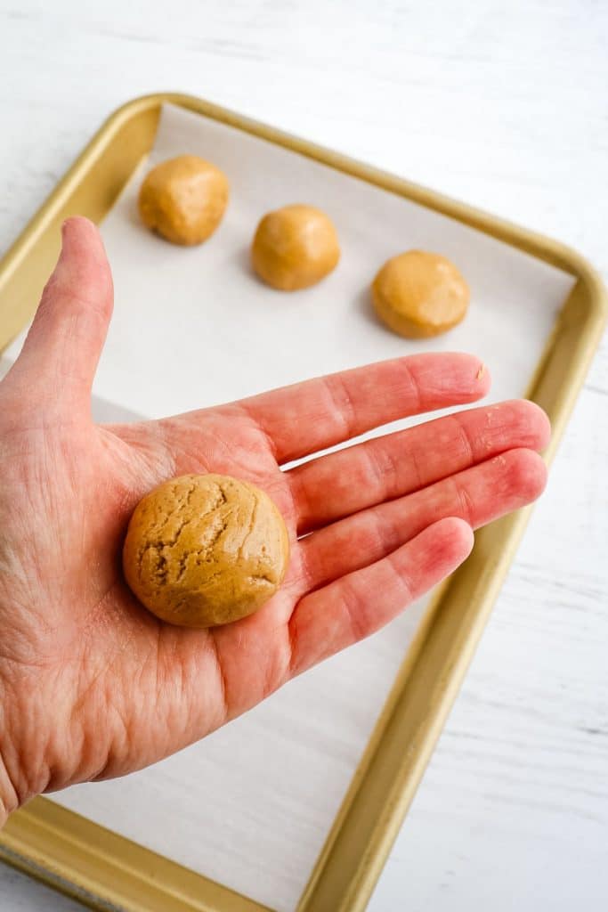 Peanut butter protein ball being formed in hand.