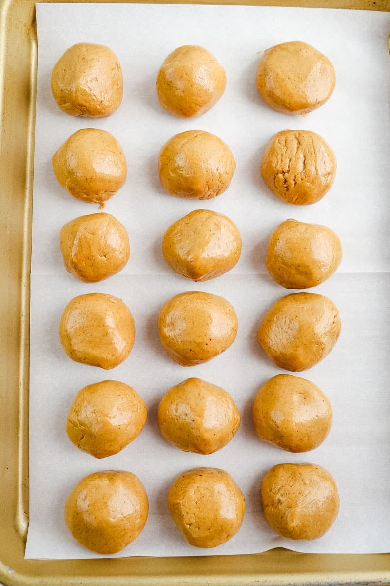 Peanut butter protein balls with protein powder placed on a lined pan.
