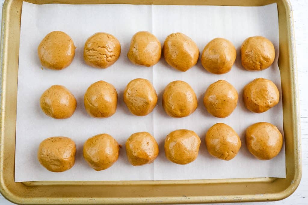 Peanut butter protein balls on a lined pan.